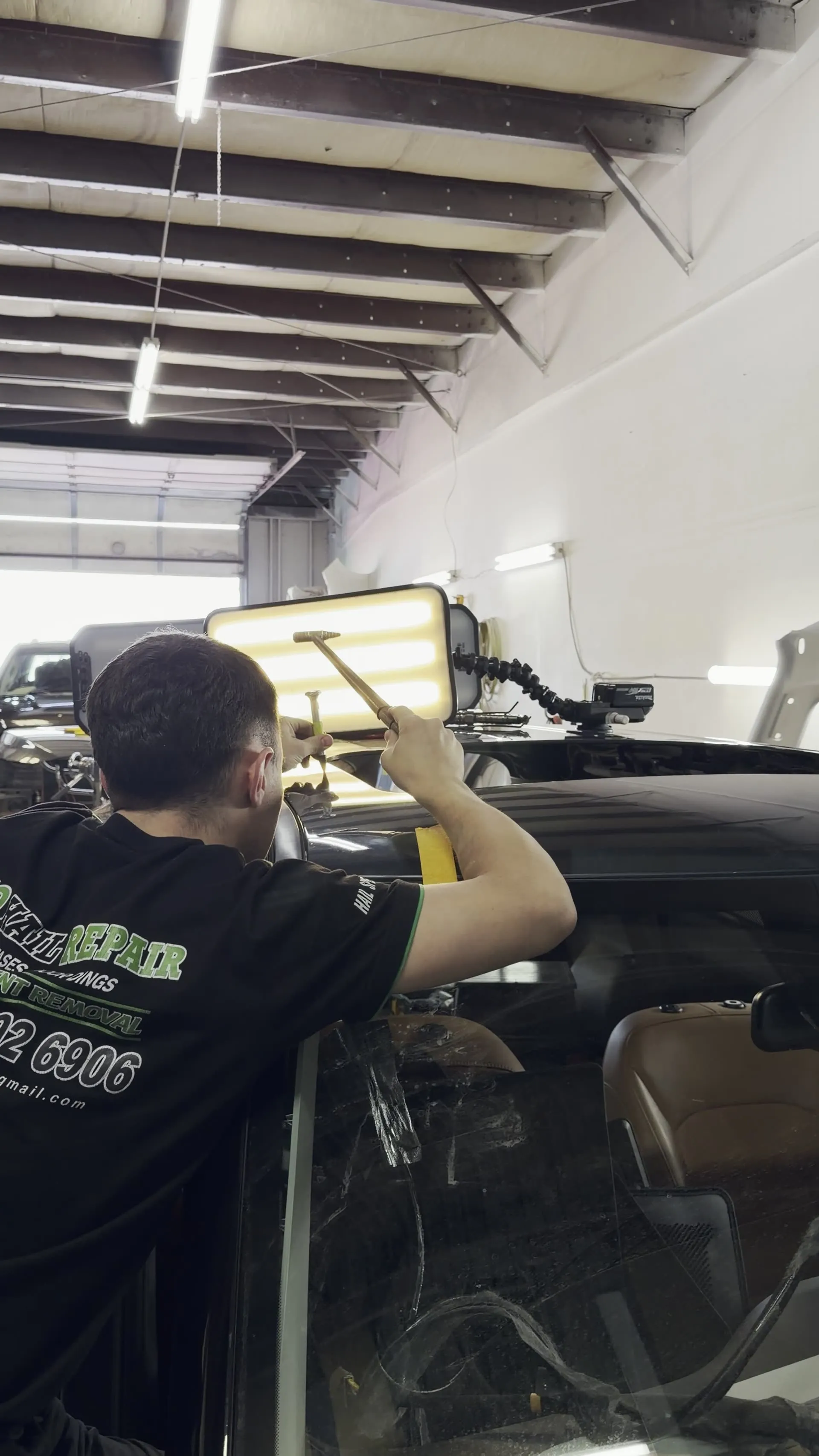 Inside the Pro Car PDR shop — technician in branded gear at the light board
