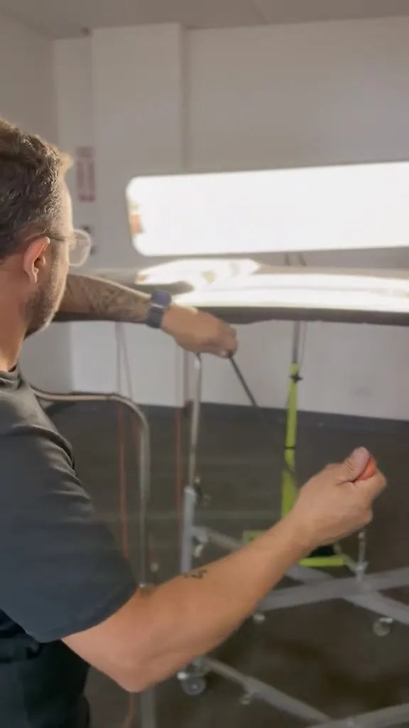 Technician working a PDR rod behind a fender