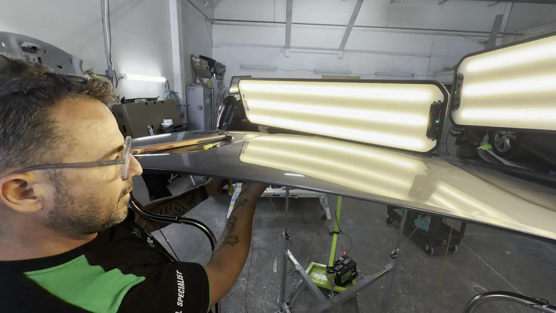 Pro Car PDR technician reforming a roof panel under twin light boards